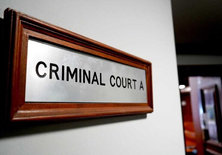 Wooden-framed metal sign reading 'CRIMINAL COURT A' mounted on a wall in a hallway of a courthouse?