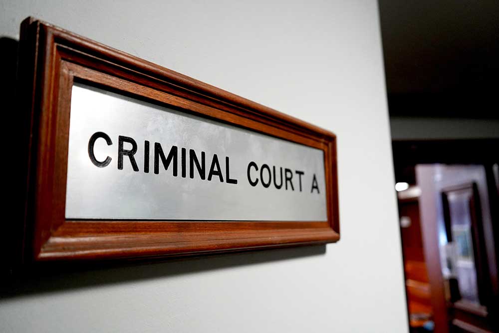 Wooden-framed metal sign reading 'CRIMINAL COURT A' mounted on a wall in a hallway of a courthouse?